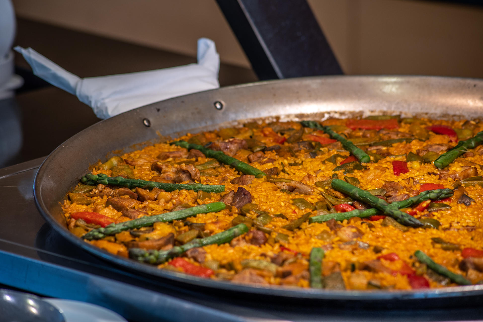 Paella de carne y verduras con pimientos costillas esparragos tomate.